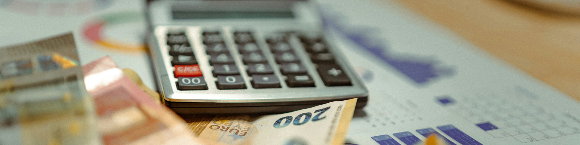 Euro notes, a calculator and a spreadsheet lying on a desk